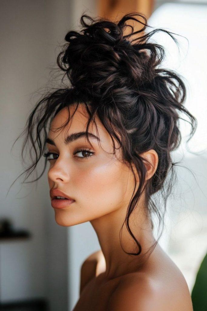 Classic messy high bun updo with loose tendrils