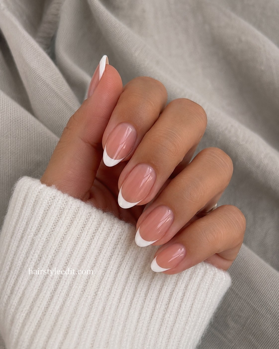 Short oval nails with a classic white French tip over a sheer pink base