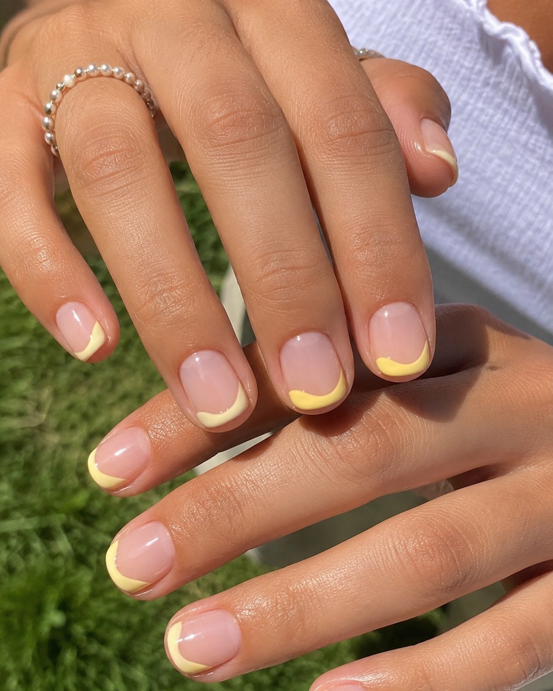 Short round shellac nails with an asymmetrical yellow swoosh French tip