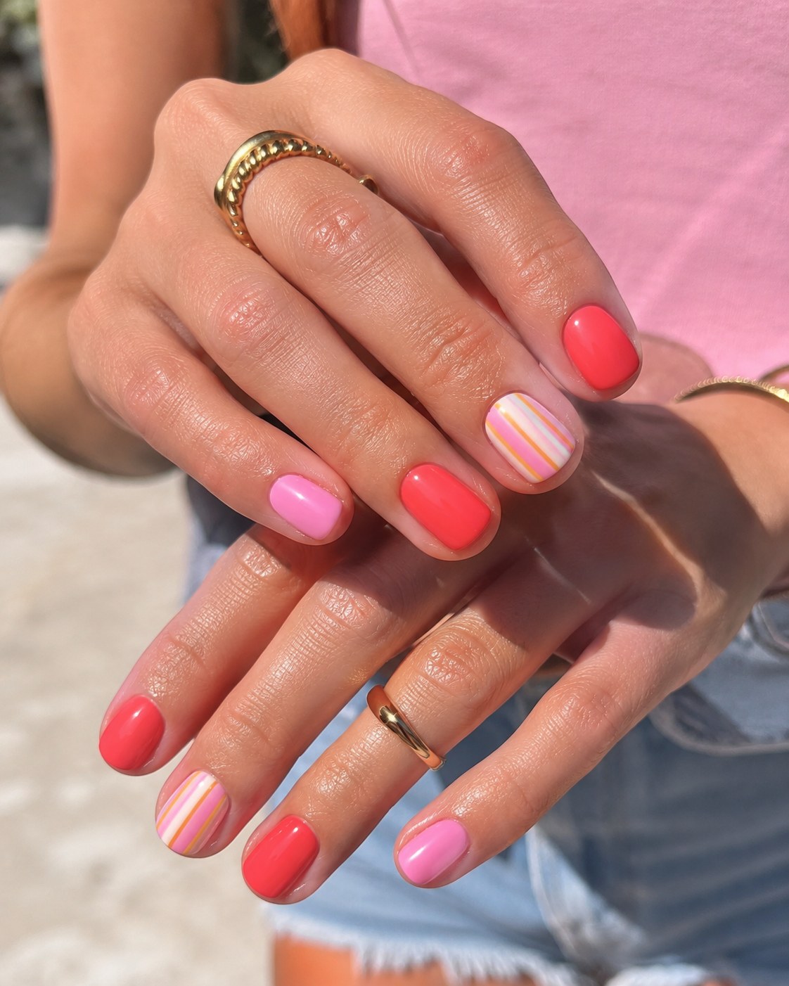 Solid coral short summer nails paired with a striped pastel candy accent nail